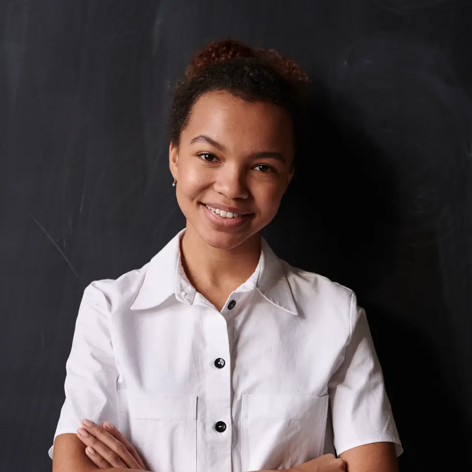 Sam Okonjo in a white shirt, smiling, against the studio chalkboard